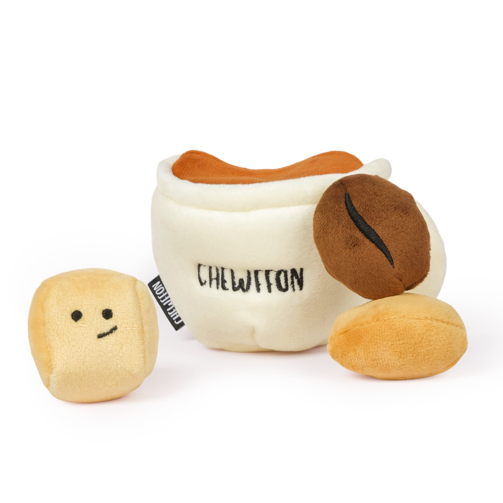 Plush toy resembling a coffee cup with a face and two beans on a white background