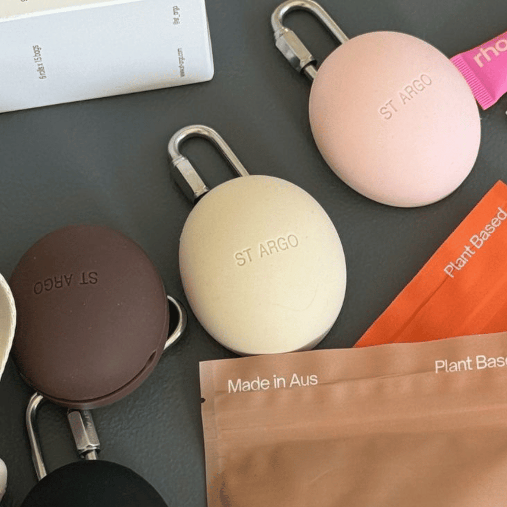 ST ARGO keychains in various colors on a dark surface with branded packaging.