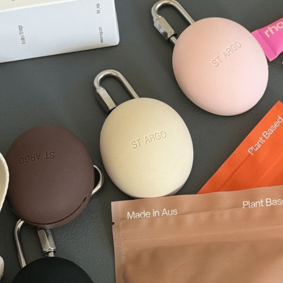 ST ARGO keychains in various colors on a dark surface with branded packaging.